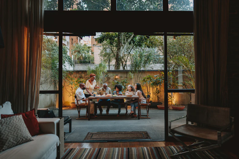 A large family gathers for a meal in a beautiful patio space outside of their home